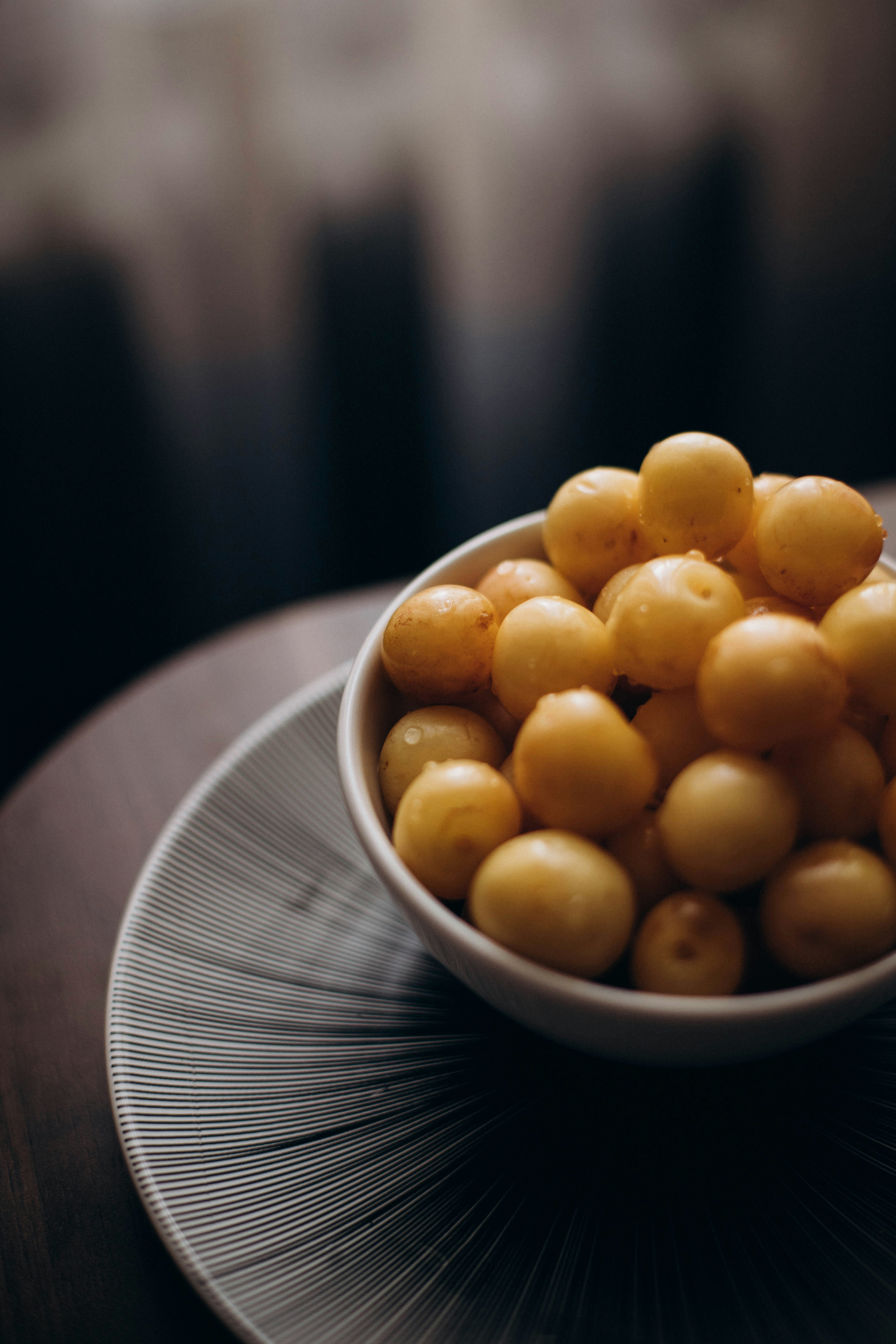 a white bowl filled with yellow fruit on top of a wooden table