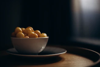 Soft natural light illuminating a rustic ceramic bowl filled with fresh fruit.