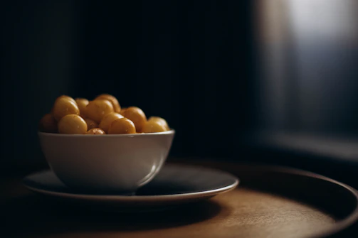 Soft natural light illuminating a rustic ceramic bowl filled with fresh fruit.