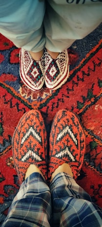 A pair of wool slippers being hand-stitched by an artisan in a cozy workshop.
