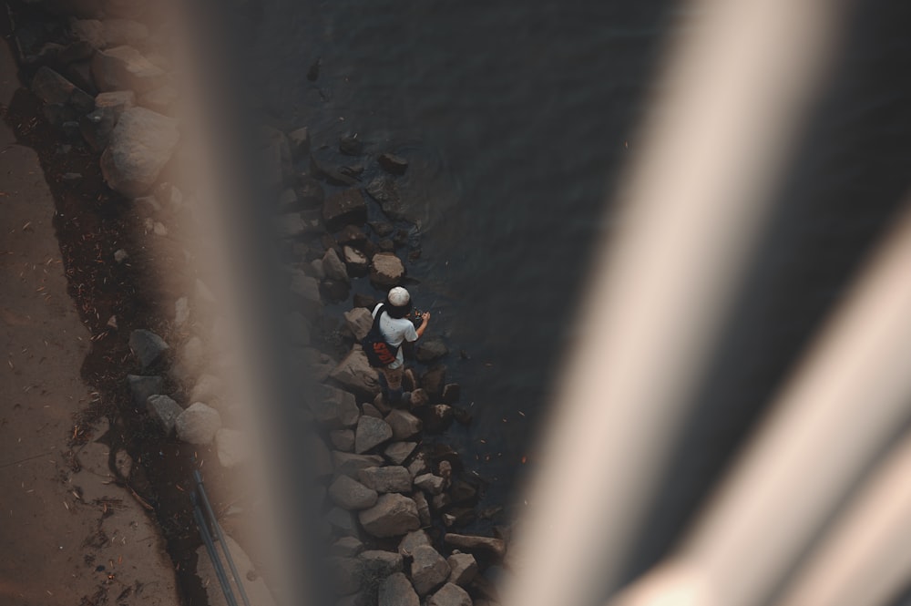 an aerial view of a man standing on a rocky beach