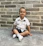A joyful child wearing the pirate design t-shirt, sitting against a concrete wall with doodle art.