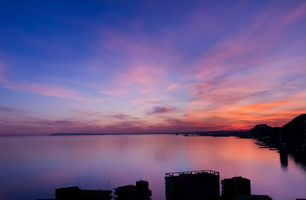 前景に建物がある水域に沈む夕日