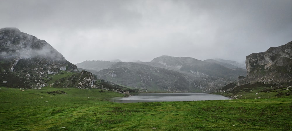a lake surrounded by mountains on a cloudy day
