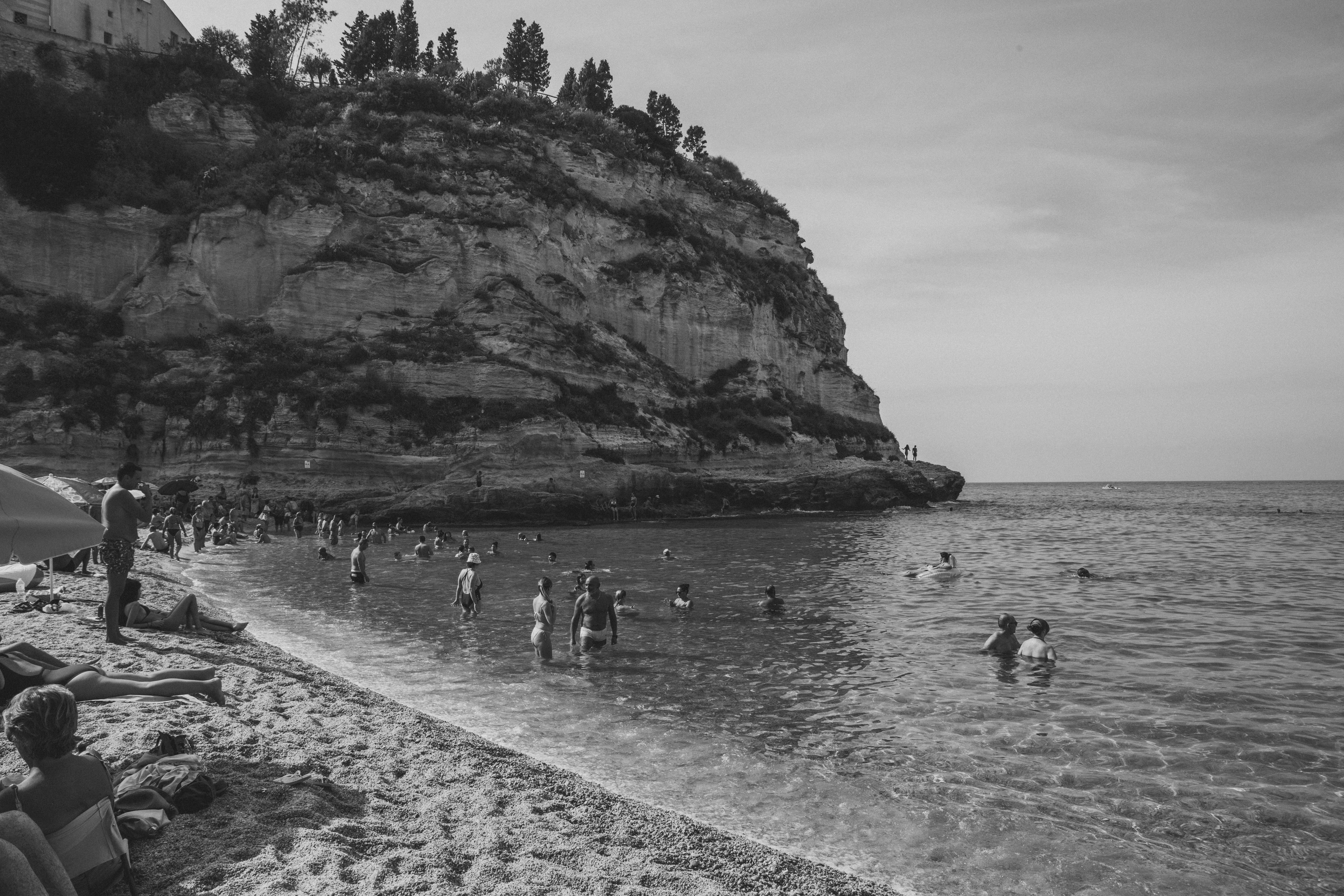 a group of people standing on top of a beach next to the ocean