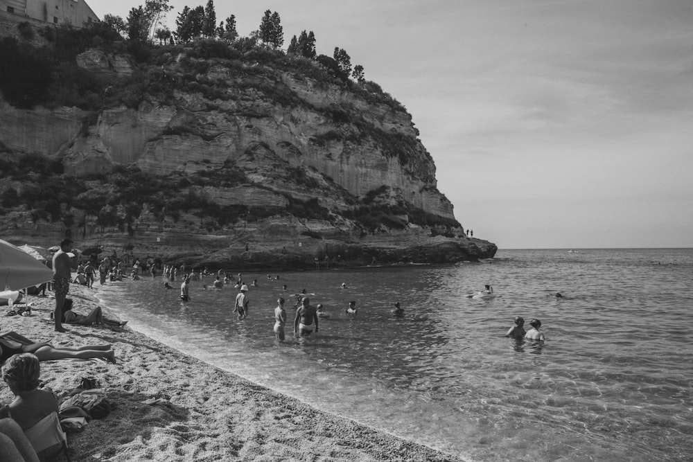 a group of people standing on top of a beach next to the ocean