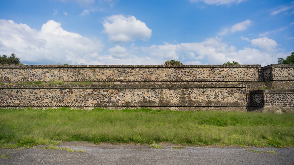 un grande muro di pietra con l'erba di fronte ad esso