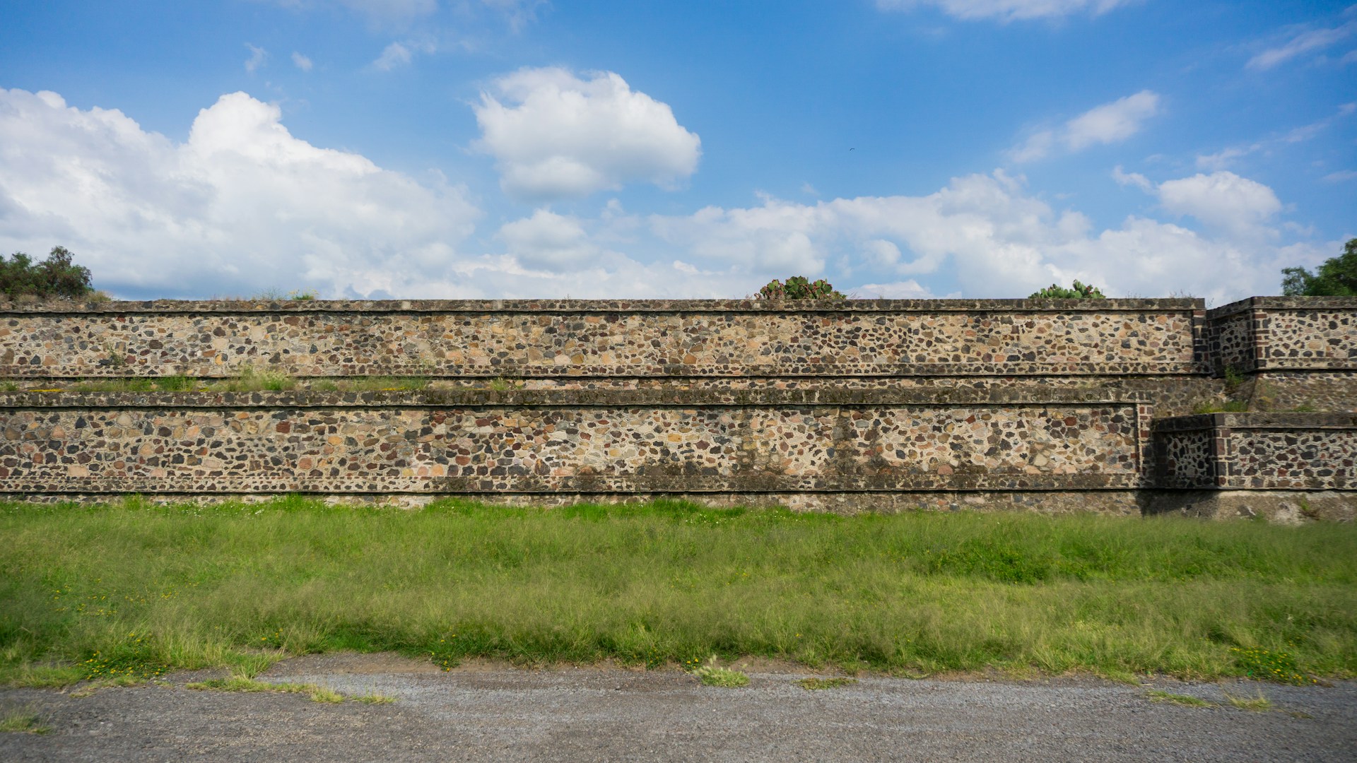 a large stone wall with grass in front of it