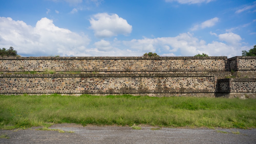 a large stone wall with grass in front of it