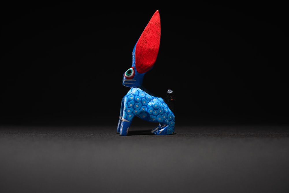 a blue and red figurine sitting on the ground