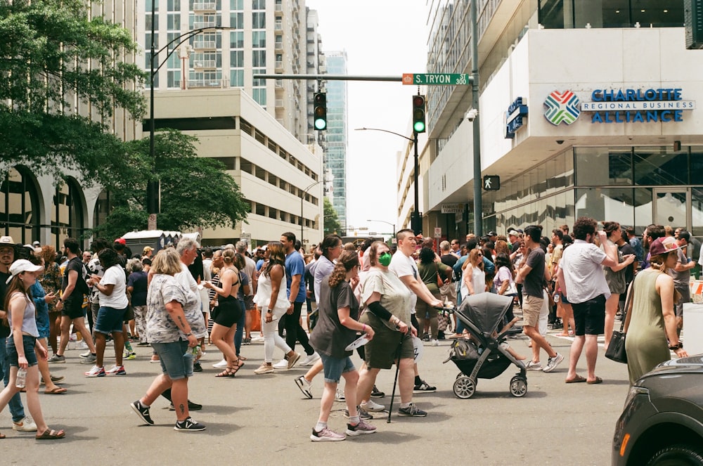 a crowd of people walking across a street next to tall buildings
