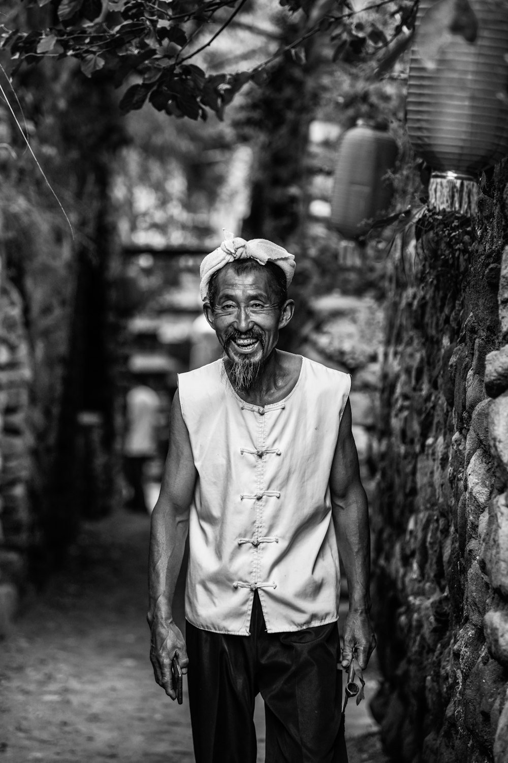 a man walking down a street next to a stone wall