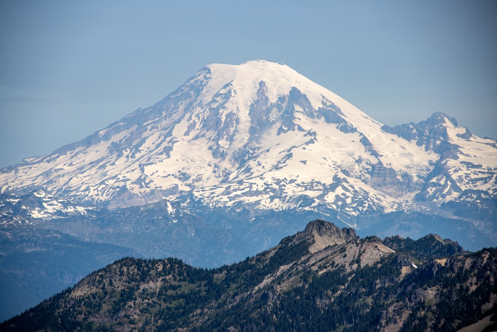 a snow covered mountain is seen from the top of a hill