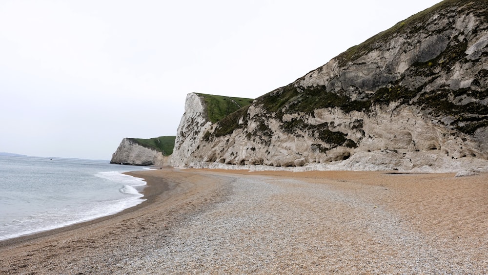 a sandy beach next to a large white cliff