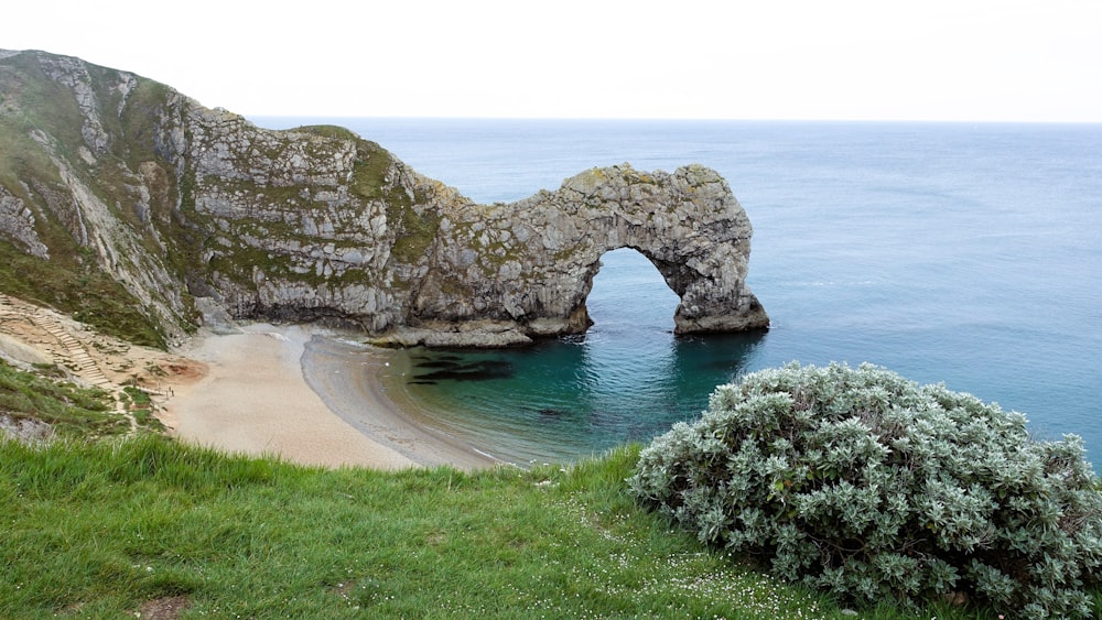 a view of a beach with a rock arch in the water