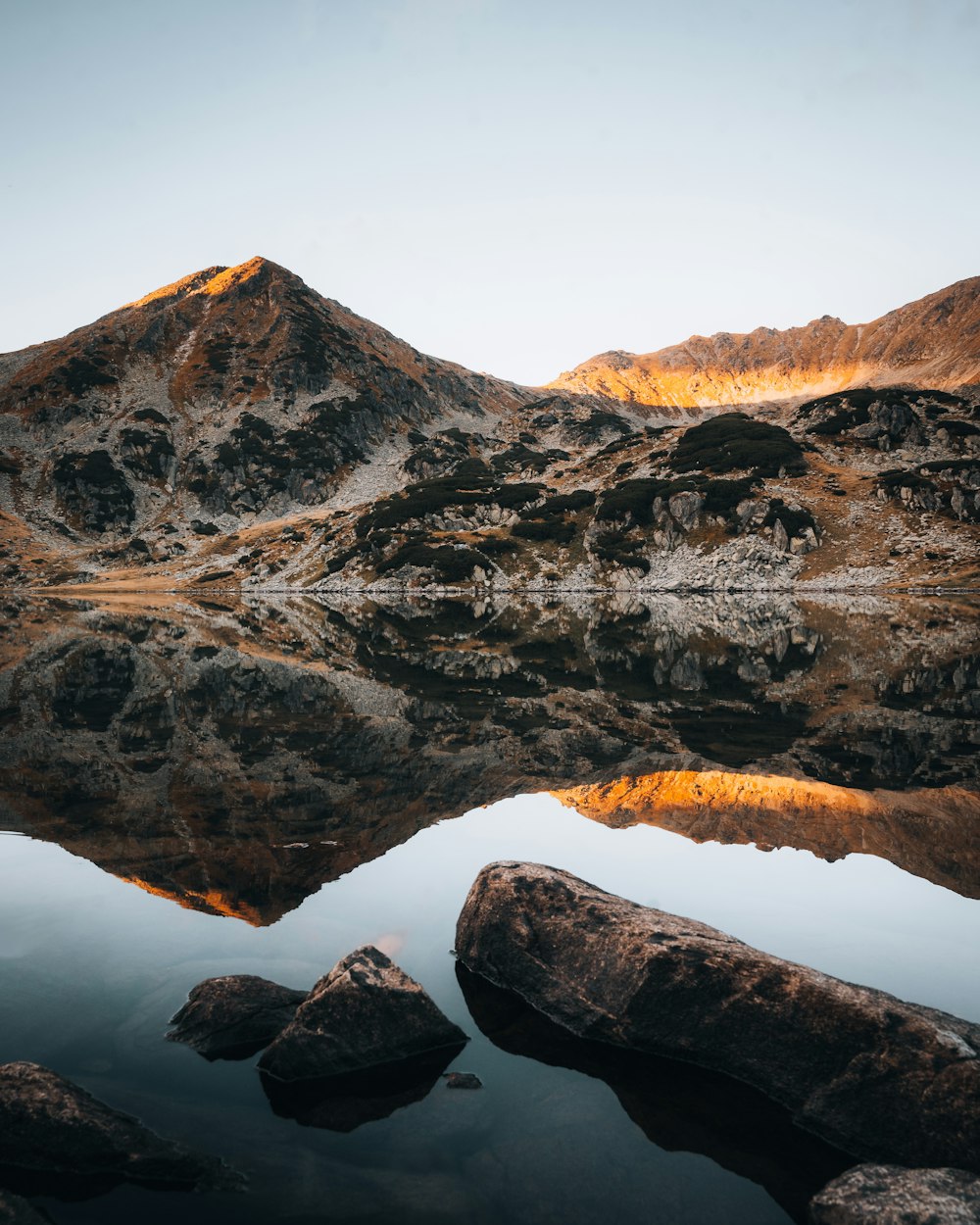 a mountain range is reflected in the still water of a lake