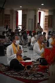 A community gathering in a sunlit room, with Dr. Ekus Ono leading a mindful meditation session.