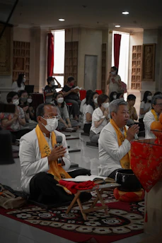 A serene group sitting in a circle chanting mantras in a softly lit room.
