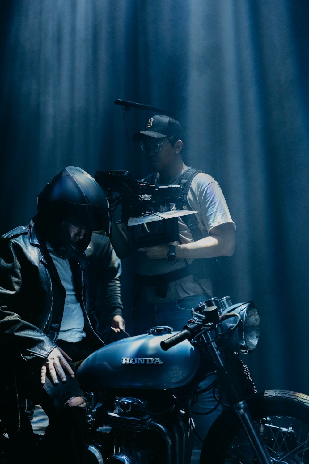 a man sitting on a motorcycle next to another man