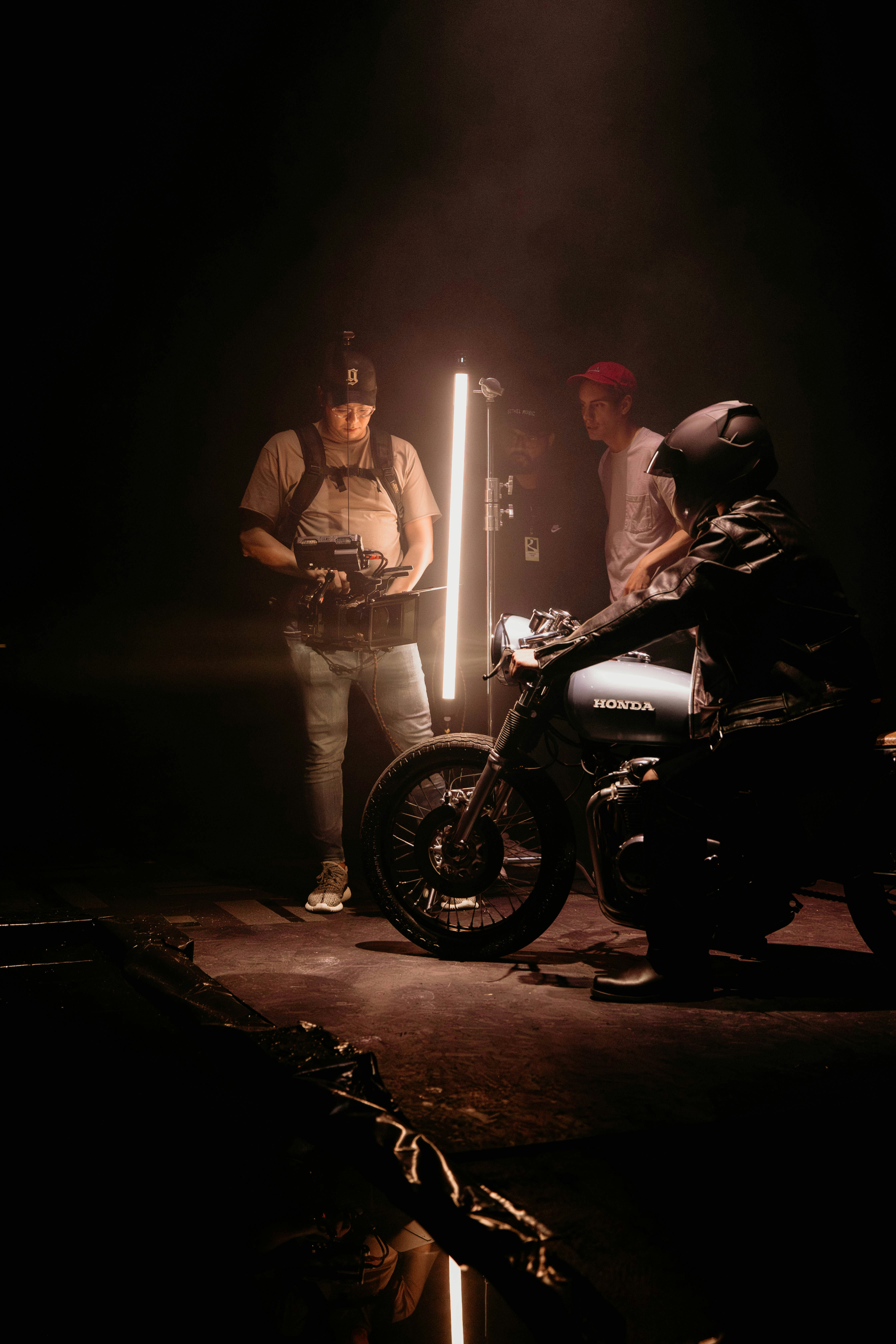two men standing next to a motorcycle in the dark