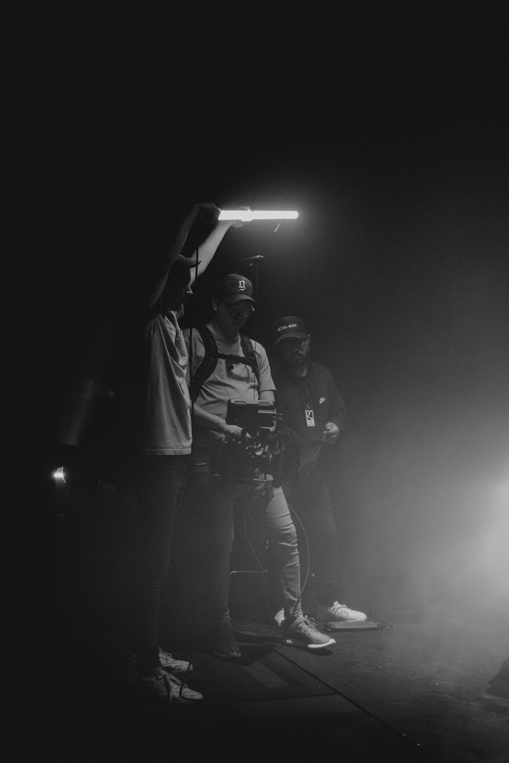 a black and white photo of three people in the dark