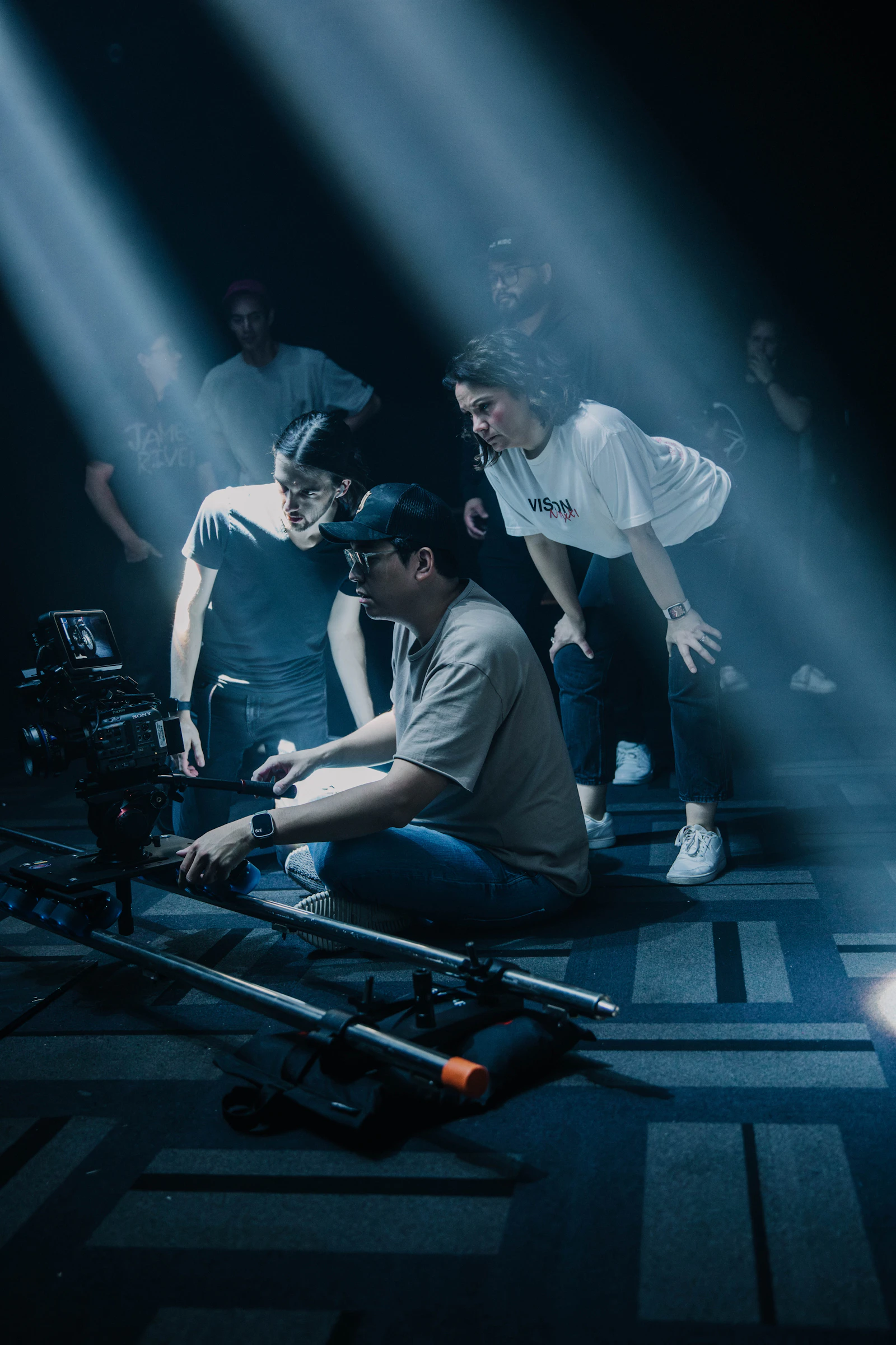 Small documentary crew standing around a camera outdoors