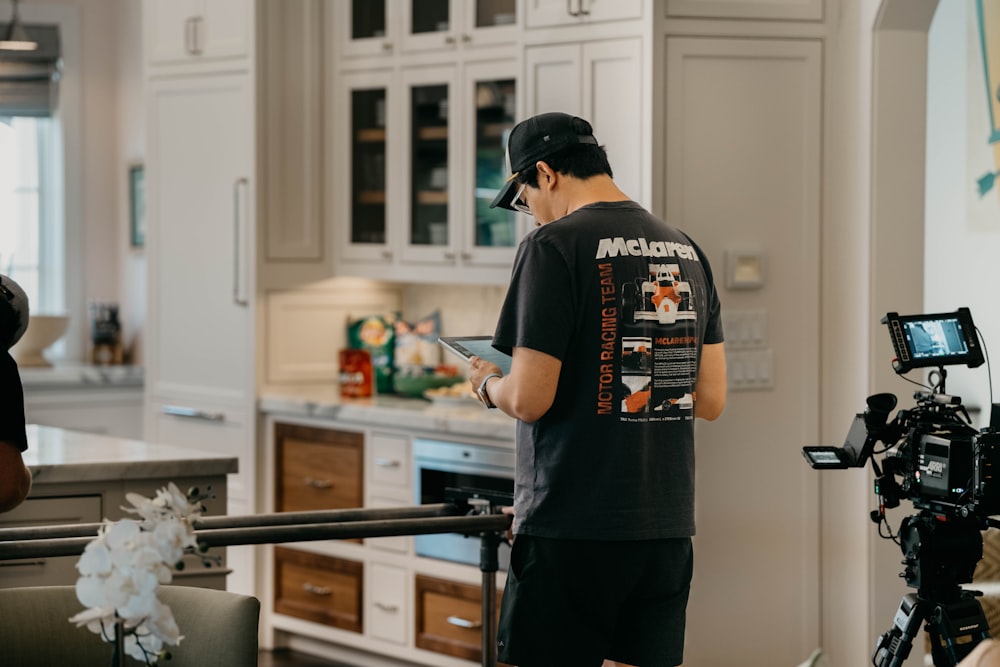 a man standing in a kitchen next to a camera