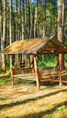 A sturdy wooden shelter nestled in a dense forest, surrounded by tall trees.