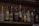 A collection of various liquor bottles displayed on a wooden shelf, featuring a mix of different brands and types such as whiskey, vodka, and liqueurs. The bottles are arranged closely together with some labels clearly visible, including colorful and unique designs.