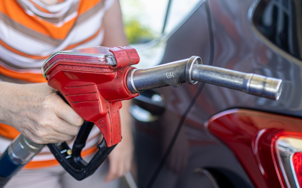 a woman filling a car with gas at a gas station