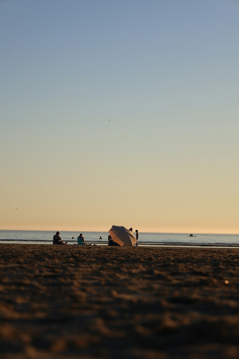 Un gruppo di persone in piedi sulla cima di una spiaggia sabbiosa