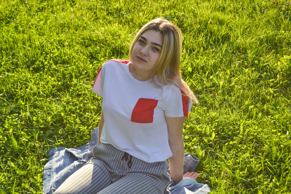 a woman sitting on a blanket in the grass