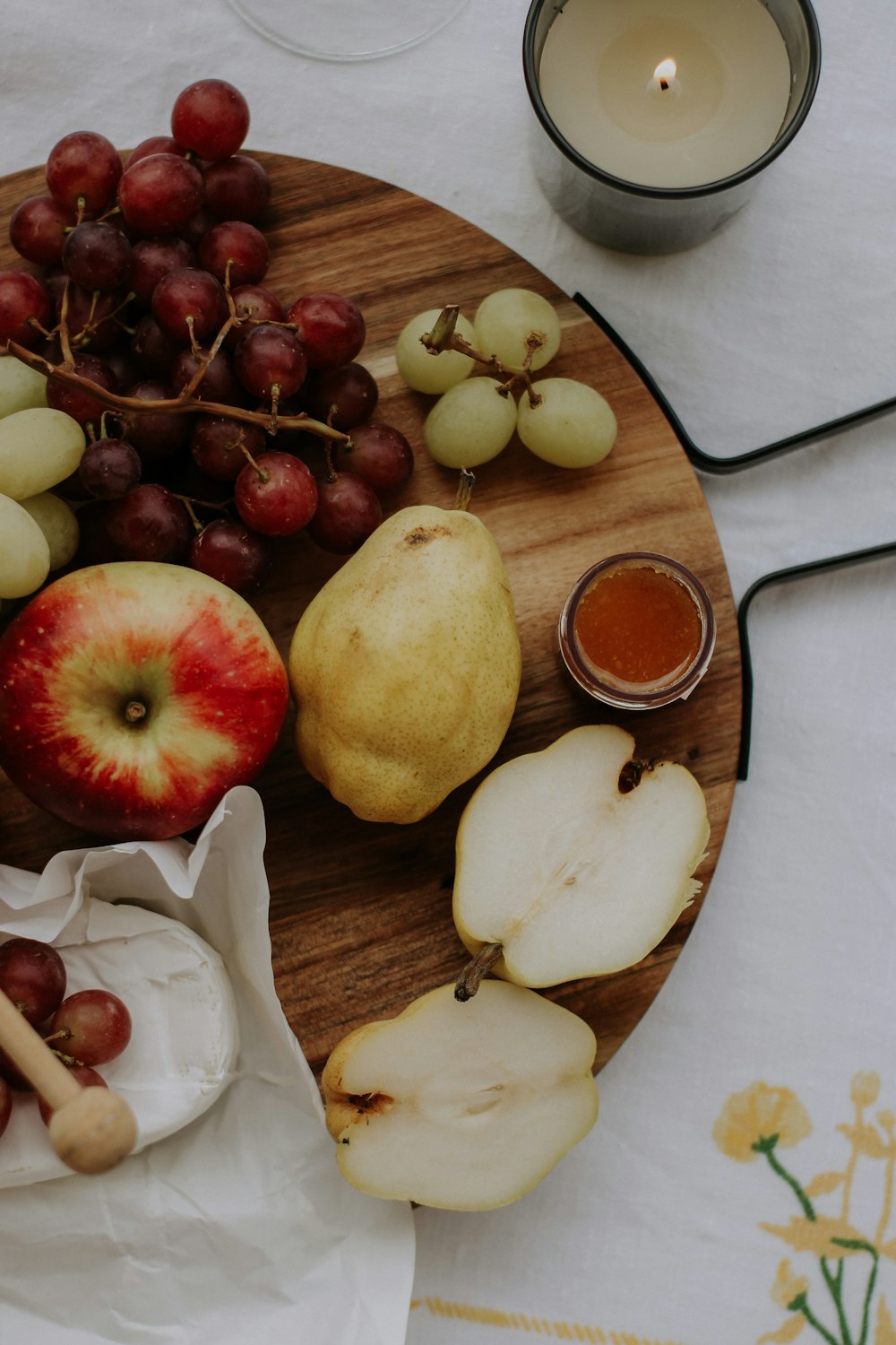 a wooden plate topped with apples, pears and other fruit