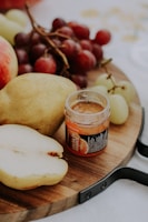 A rustic wooden serving tray with natural edges, styled with fresh fruits and cheeses.