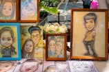 A colourful display of original caricature artworks hanging in a gallery.