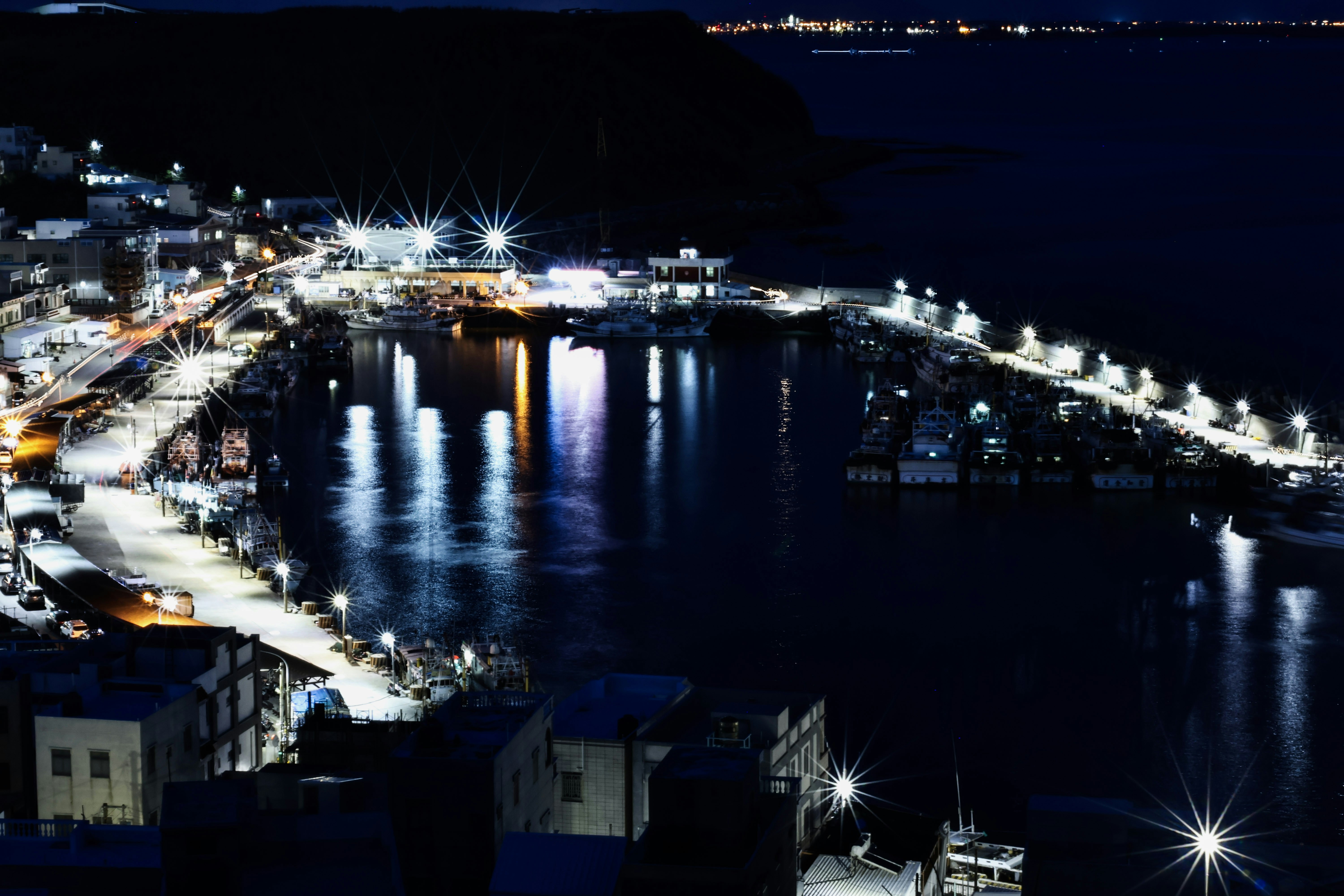 a night time view of a harbor with boats and lights