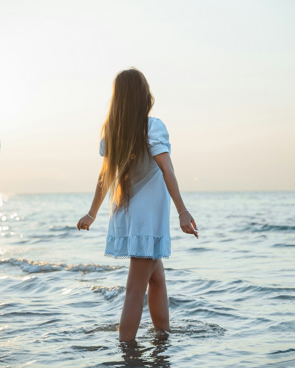 a girl standing in the water at the beach
