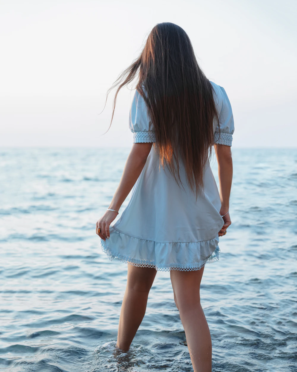 Woman standing in the water, looking out at the ocean