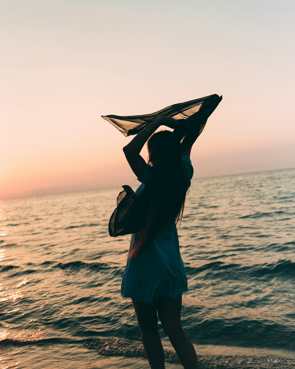 a woman standing on top of a beach next to the ocean