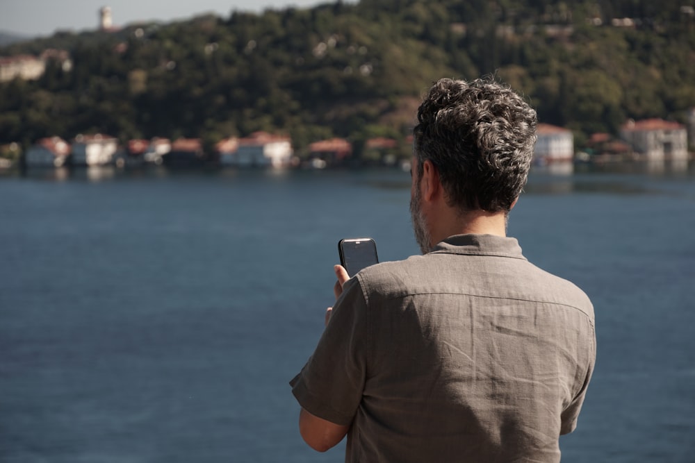 um homem tirando uma foto de um corpo de água