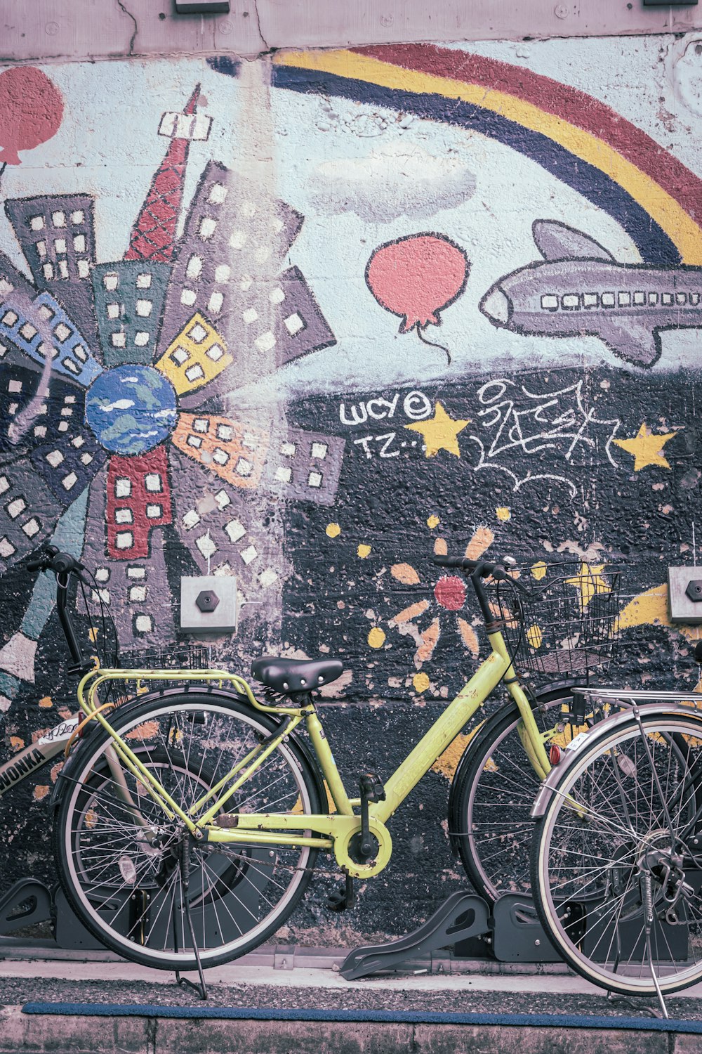 a yellow bike parked next to a wall covered in graffiti