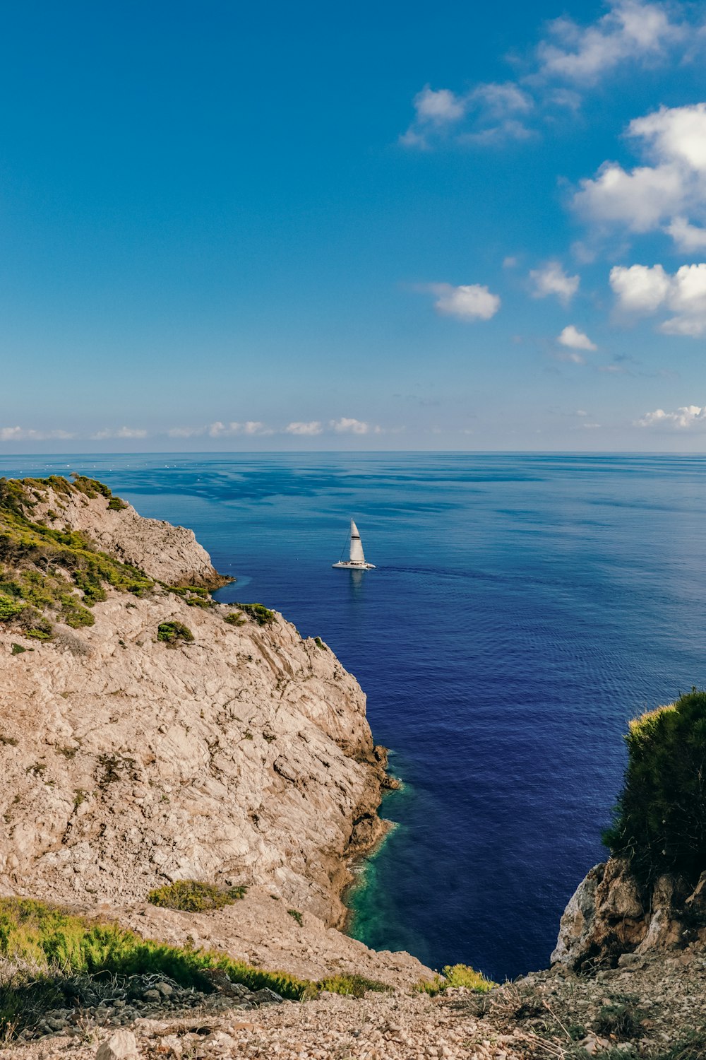 a sailboat in the ocean near a rocky cliff
