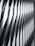 The image features a modern architectural facade with a geometric, repeating pattern of overlapping and protruding panels. The design creates a sense of depth and dynamism, with sharp angles and shadows accentuating the three-dimensional effect.