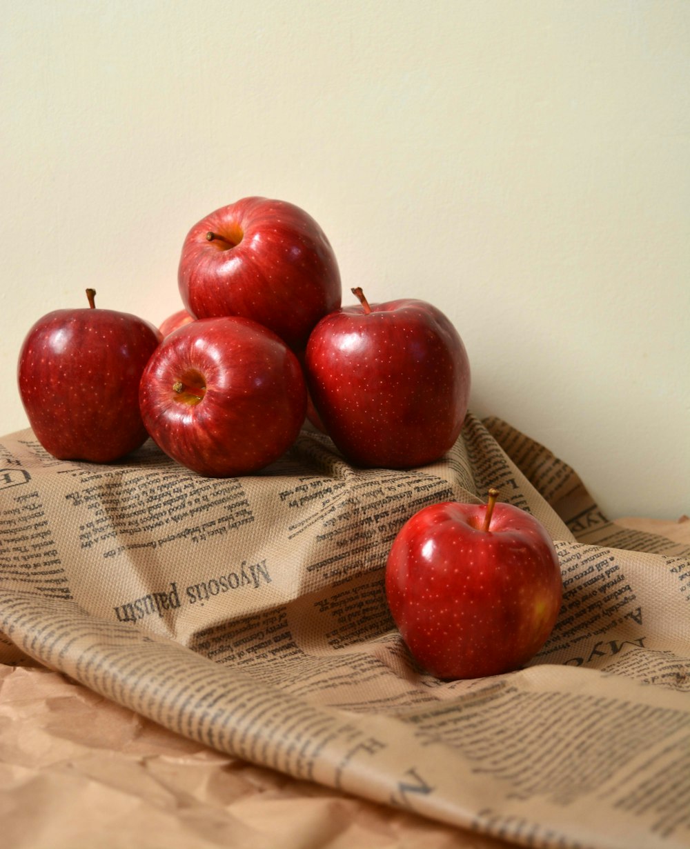 a pile of red apples sitting on top of a newspaper