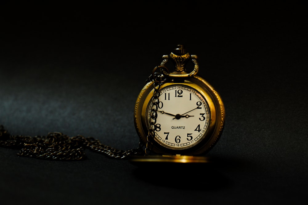 a gold pocket watch sitting on a chain