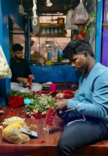 Artisan arranging traditional paddy torana door hangings in a cozy, sunlit room.