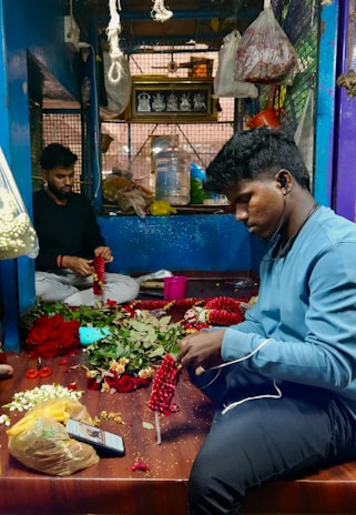 Artisan arranging traditional paddy torana door hangings in a cozy, sunlit room.