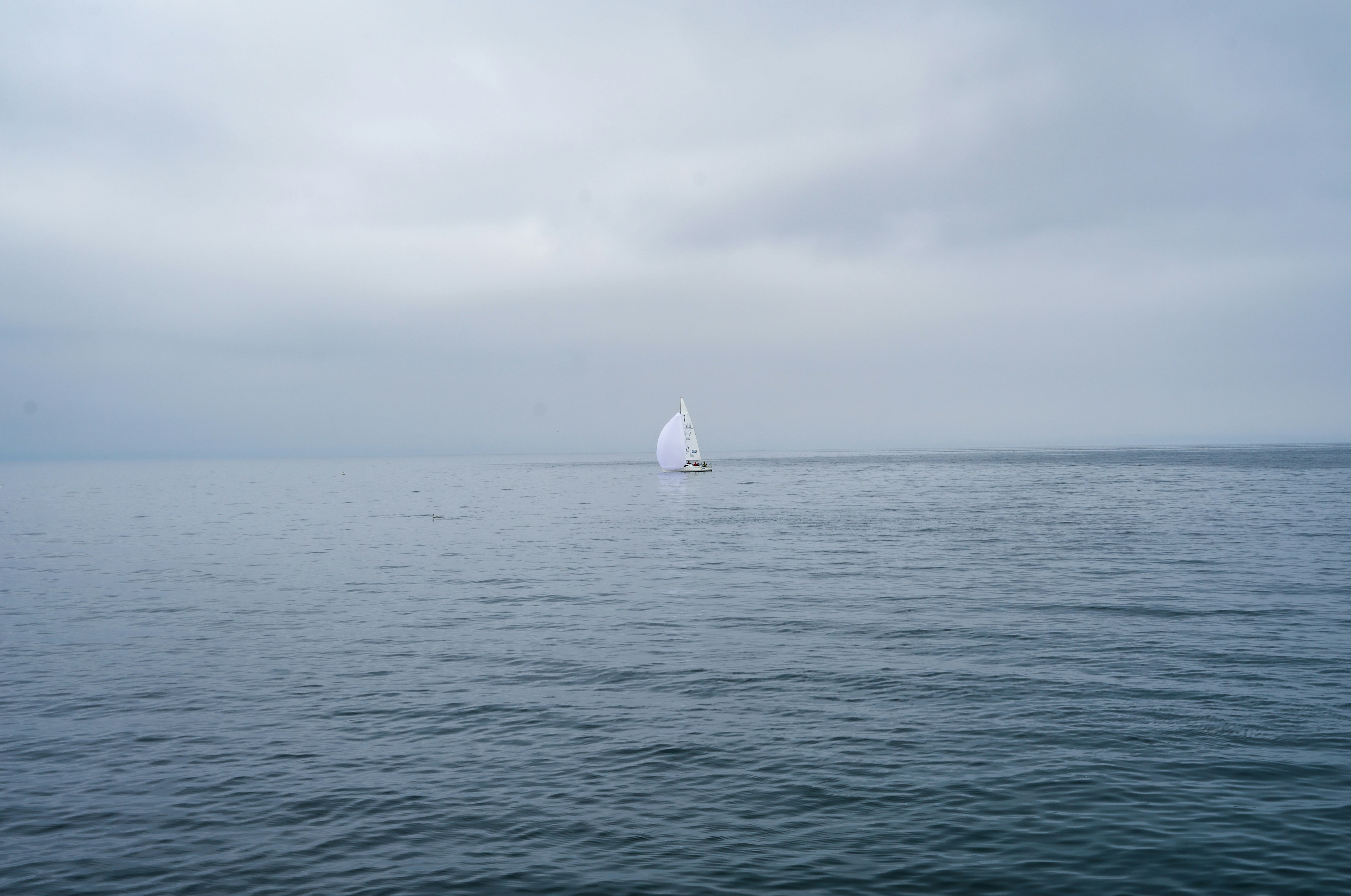 a sailboat in the middle of the ocean on a cloudy day