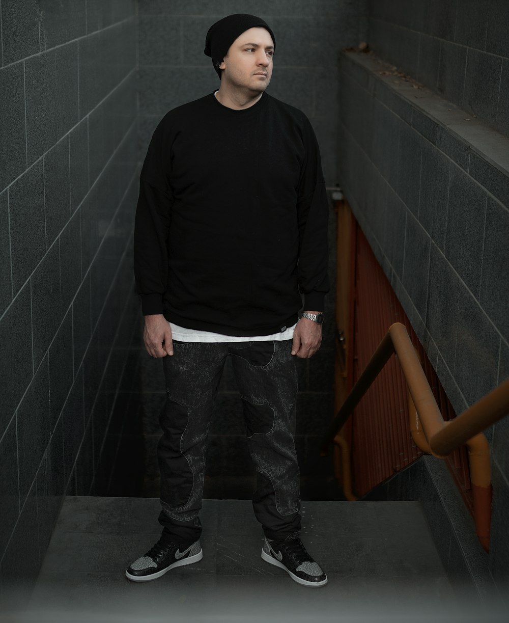 a man in a black shirt standing in a stairwell