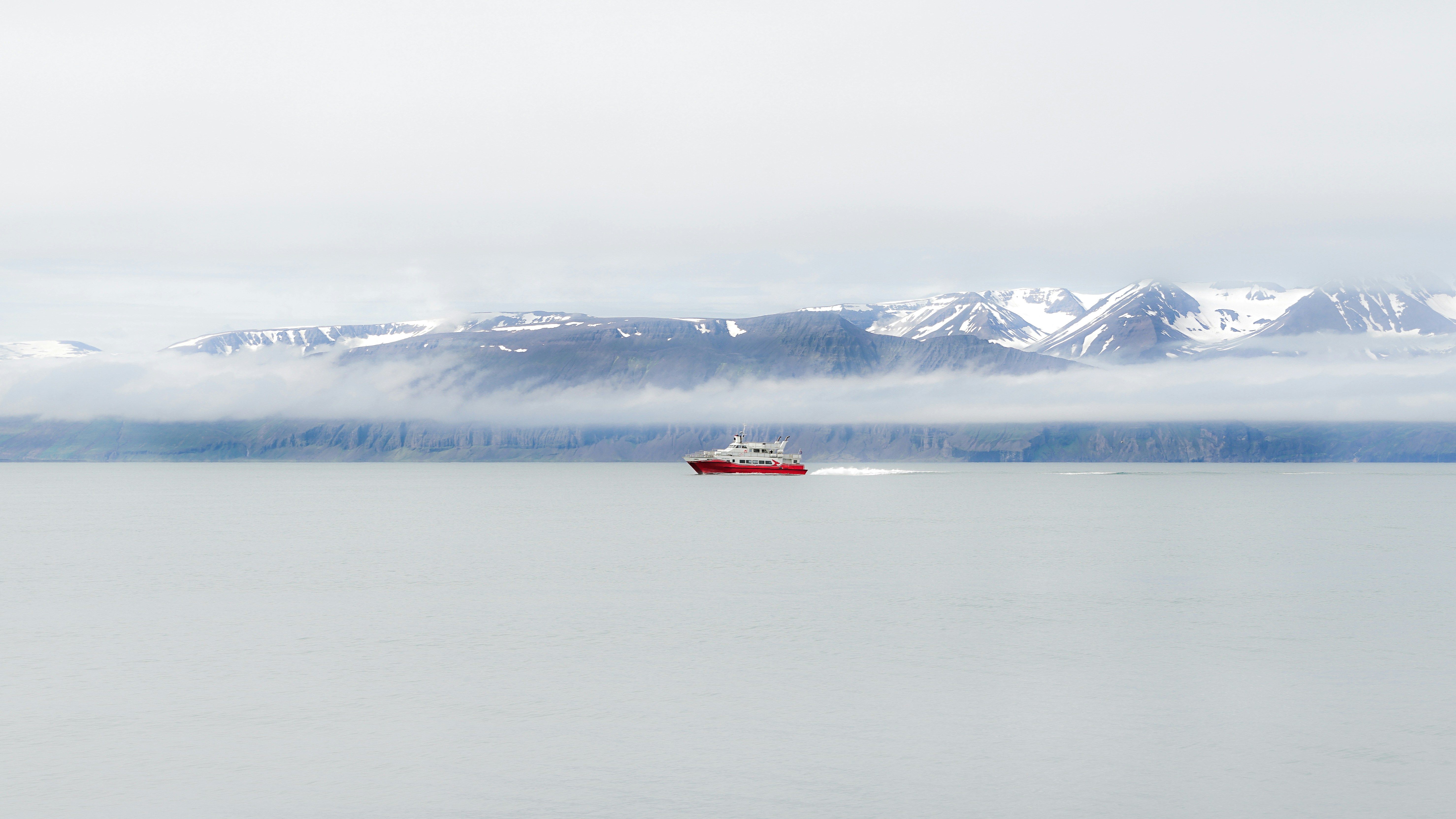 a red boat in the middle of a large body of water